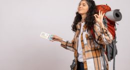 A woman with a backpack holds a credit card, ready to make a purchase or payment